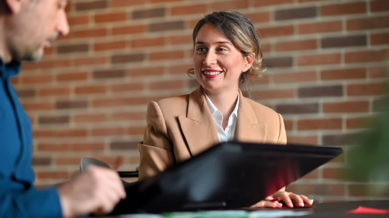 Man and woman discussing plans on a screen at the table, in an office