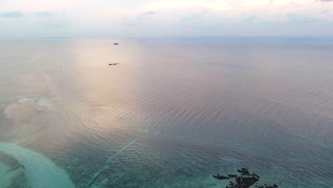 Sandy-beach-with-tropical-resort-buildings-and-ocean-horizon,-aerial-view