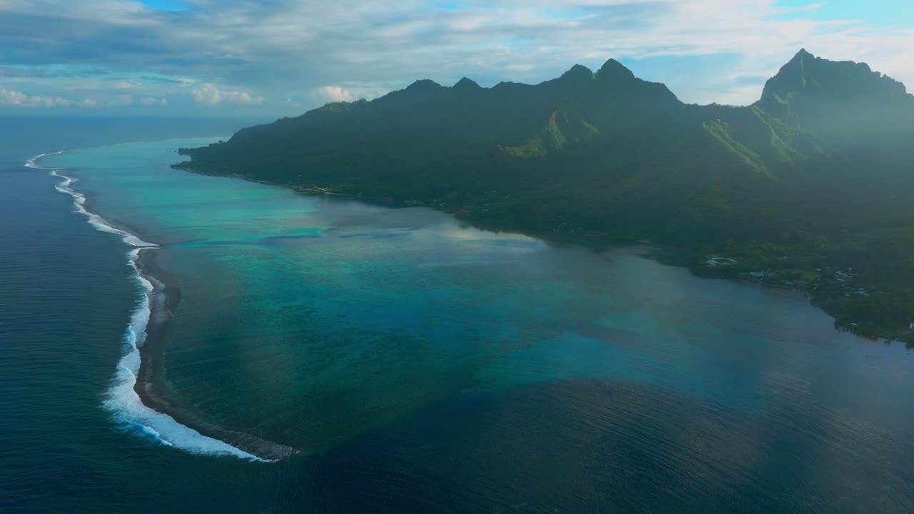 Morning sunrise Moorea island Cooks Opunohu bay French Polynesia aerial drone lagoon coral reef Mount Mauaroa Tohivea Rotui jagged peaks Haapiti Paopao Pacific Ocean blue sky sun flare backwards