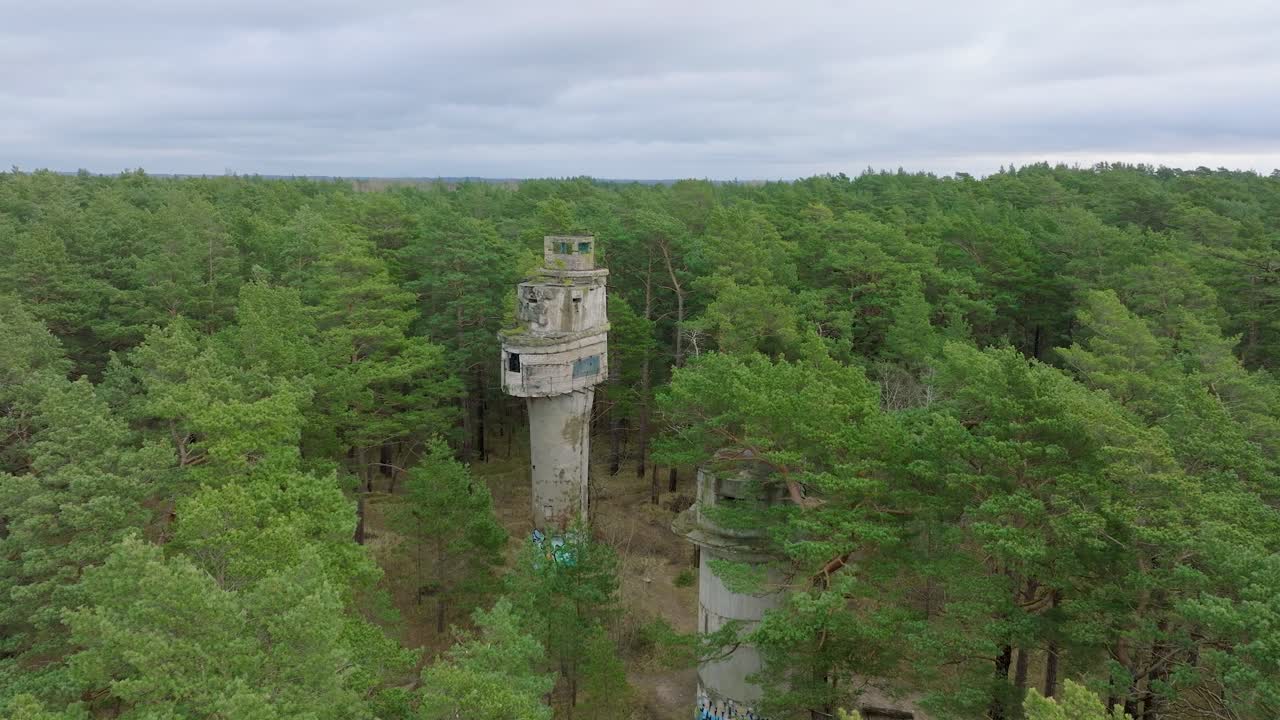 establecimiento de una vista aérea de la antigua torre de vigilancia de observación de hormigón militar soviética, bosque de pinos, liepaja, patrimonio militar, bosque nórdico, gran tiro de drones avanzando