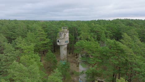 establishing aerial view of old soviet military concrete observation watchtower, pine tree forest, liepaja , military heritage, nordic woodland, wide drone shot moving forward