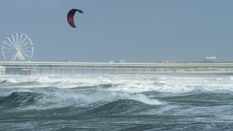 stormy beach with kitesurfing and pier