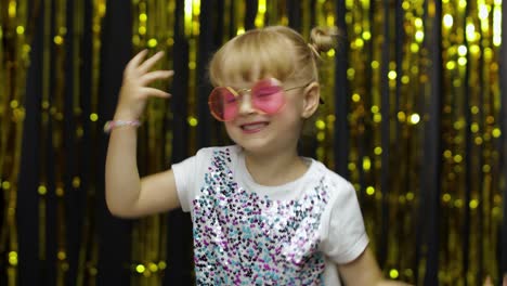 niño bailando, celebrando la victoria, haciendo tonterías. niña posando en el fondo con cortina de aluminio