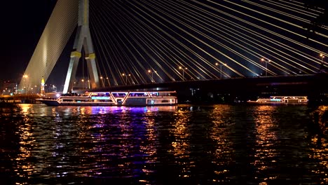 recreational boats with lights are deployed on the river under the cable bridge. part 1