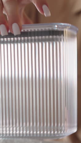 woman puts lid on transparent plastic container and examines utensil sitting at table in kitchen. female assesses quality and ease of use of purchase closeup