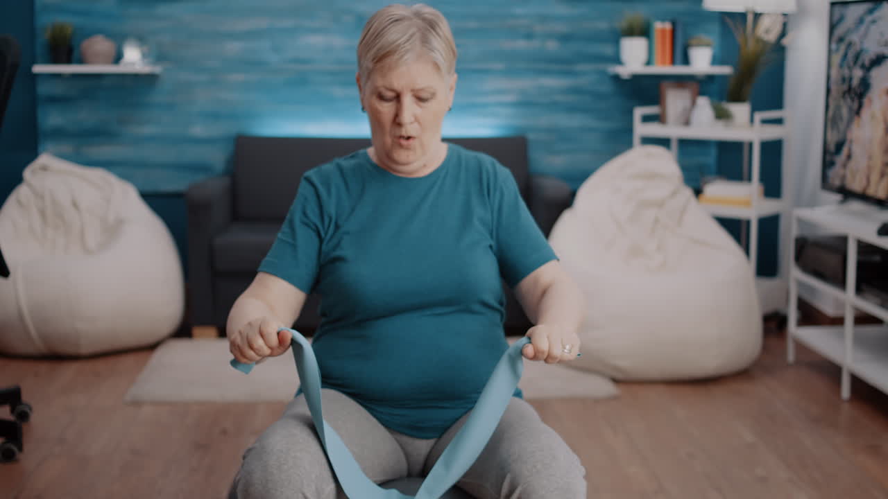 Elder woman pulling resistance band to stretch muscles arms