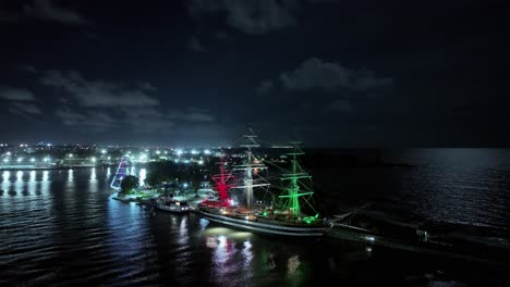 sailing ship amerigo vespucci moored at punta torrecilla with santo domingo cityscape at night, dominican republic