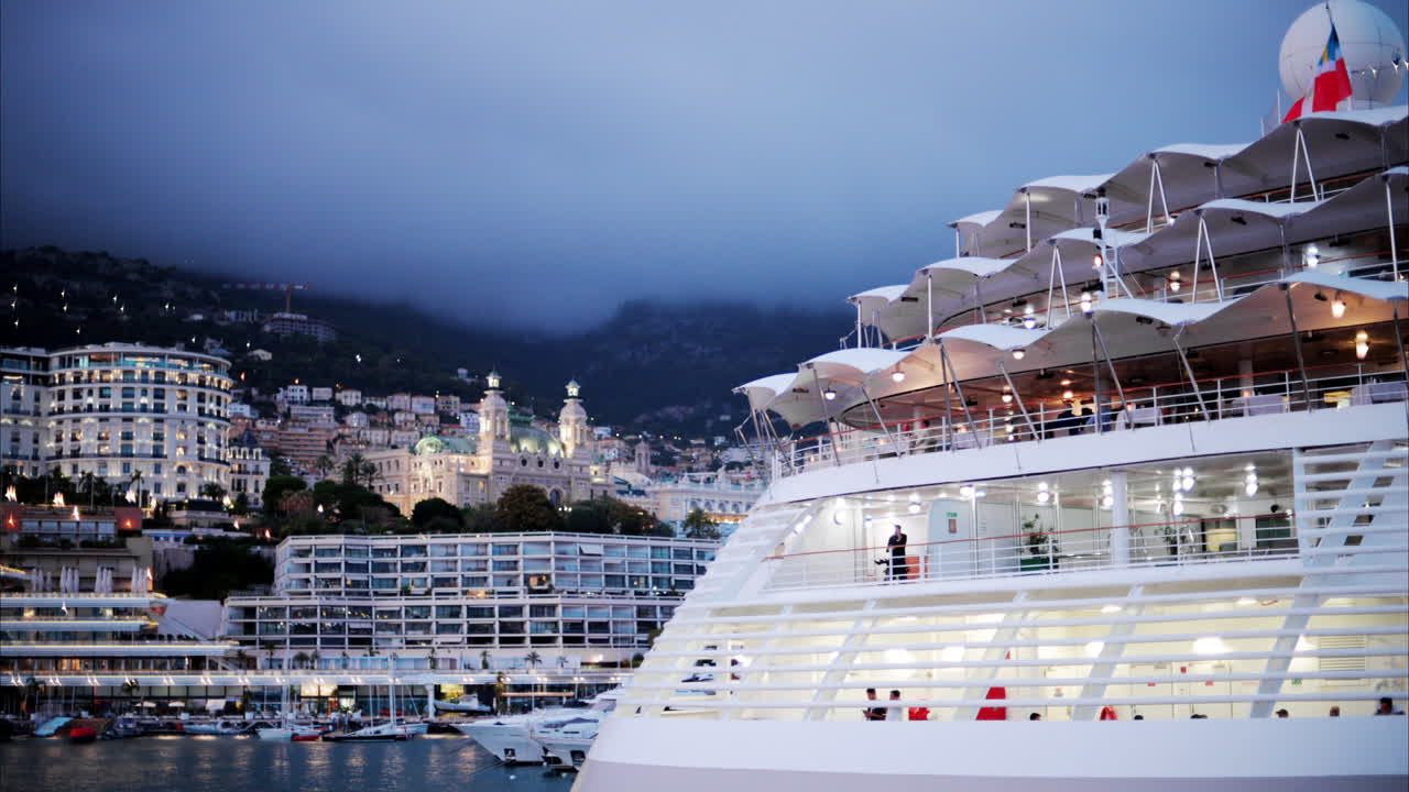 Boats docked in the Monaco Marina with the skyline of the city on the background in the evening