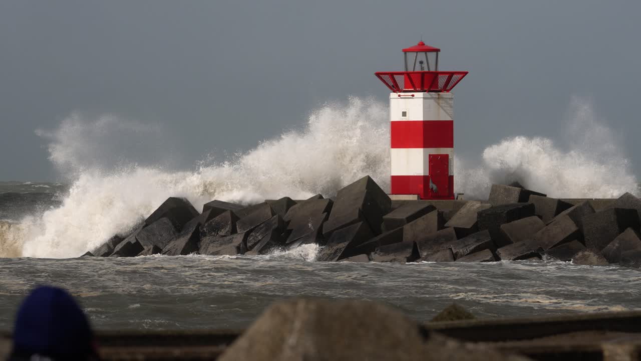 el mar embravecido rompe sobre el embarcadero y el faro en la costa de scheveningen, la haya, países bajos