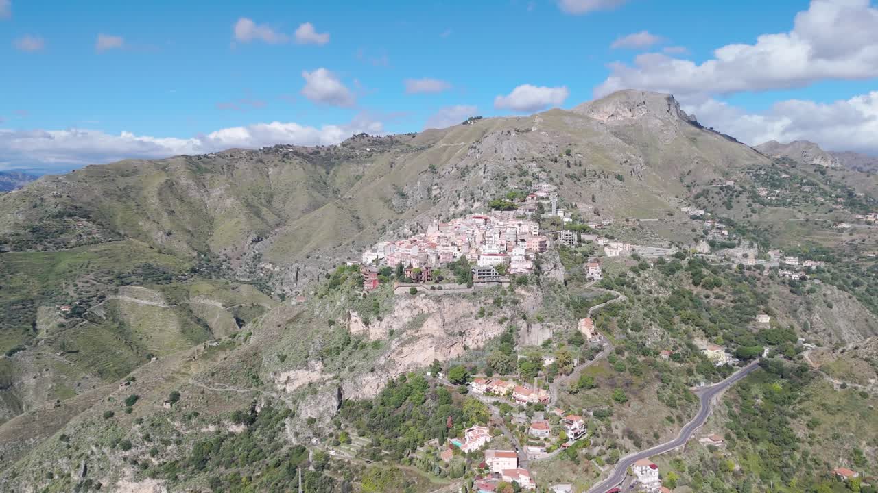 Vista aerea da drone di Castelmola, Sicilia, con montagne sullo sfondo, filmato 4K 60FPS in stile cinematografico che mostra lo storico borgo collinare, i tetti e il paesaggio mediterraneo