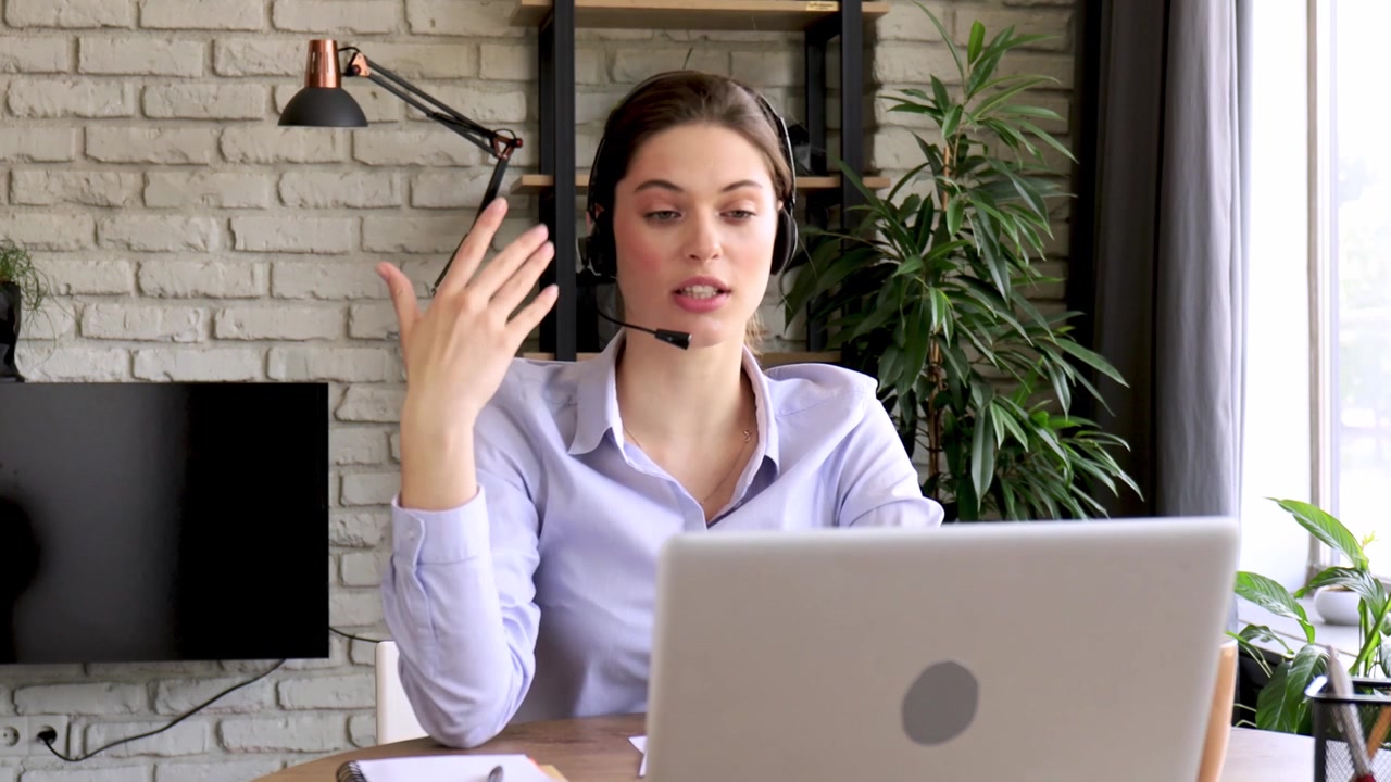 Giovane donna con auricolare che parla durante una riunione online