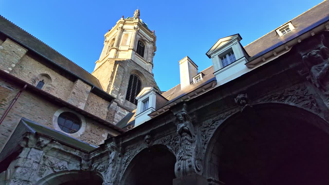 Low angle shot showing the dark stone arches and the illuminated bell tower of Notre-Dame en Saint-Melaine Church in Rennes, with a slight backward camera movement