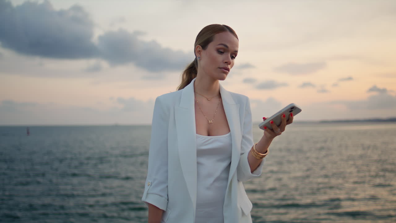 스마트폰을 사용하는 사업가 여성: 해가 지는 가까운 곳에서 여성이 전화를 끝니다.