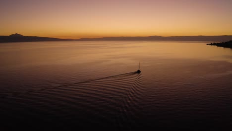 Aerial-shot-overtaking-sailboat-on-Lake-Léman-with-beautiful-sunset-colors-In-front-of-Cully,-Lavaux---Switzerland