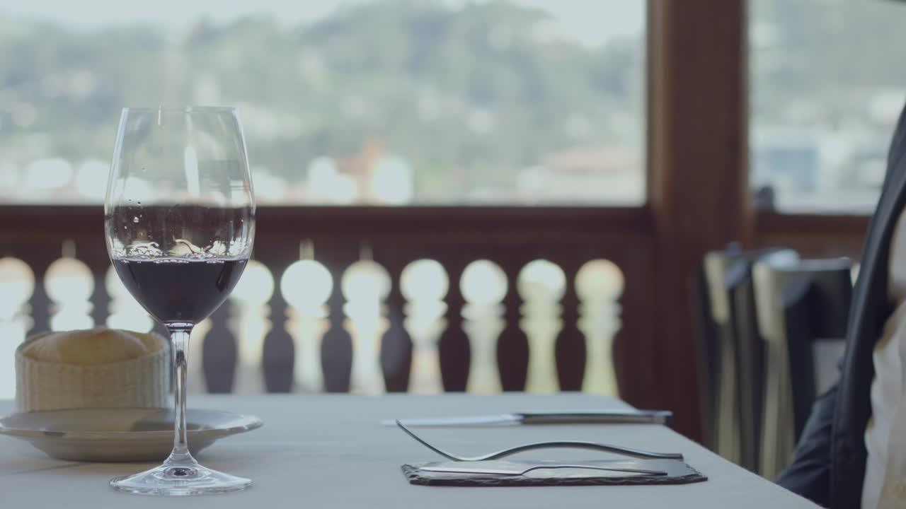 A waiter places a gourmet plate of meat with sauce and vegetables on an elegant table