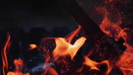 burning fire with sparks. red and orange flame surging up. smoldered black logs in fire on the dark background. slow motion.