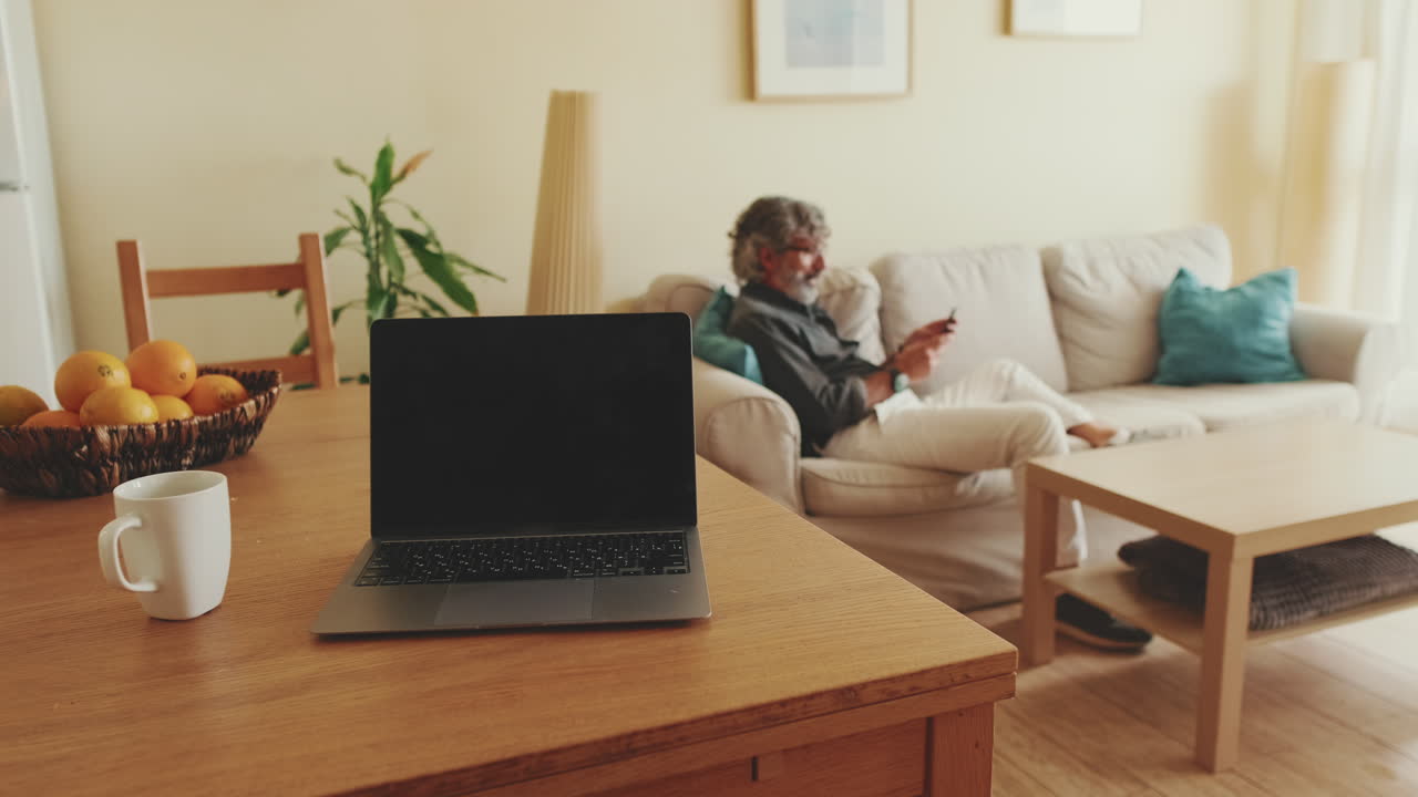 A cozy living room with a laptop and a man relaxing on the couch