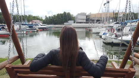 Cinematic-shot-of-a-woman-swinging-and-in-the-background-you-can-see-a-sports-dock