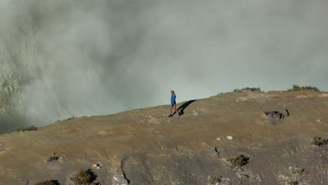 woman hike along edge of active volcano, impressive view of crater lake, aerial