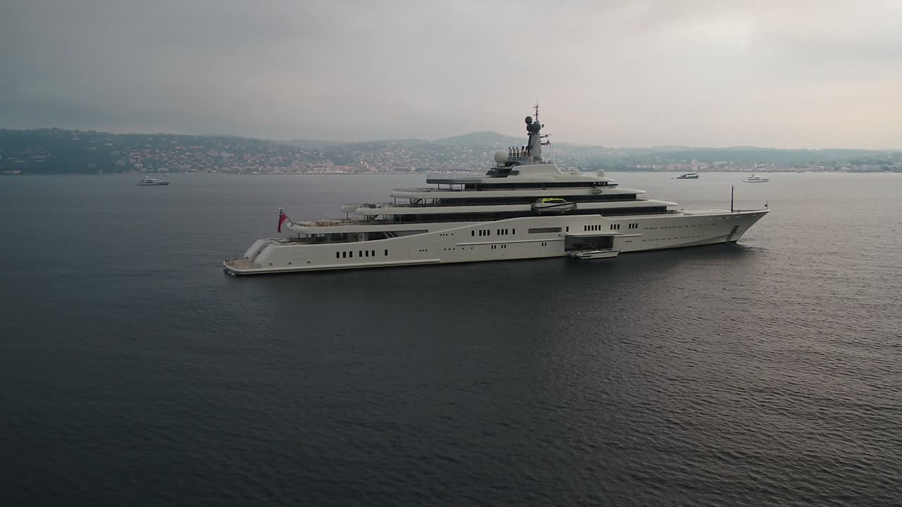 Grande yacht a vela lussuoso e costoso che galleggia in un paesaggio marino costiero al tramonto