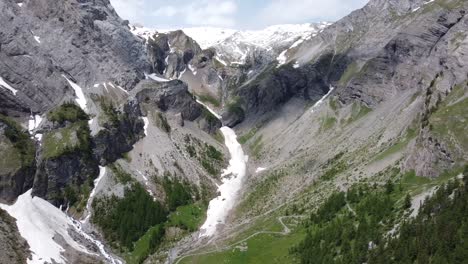 drone flight through a green valley with some snow in switzerland