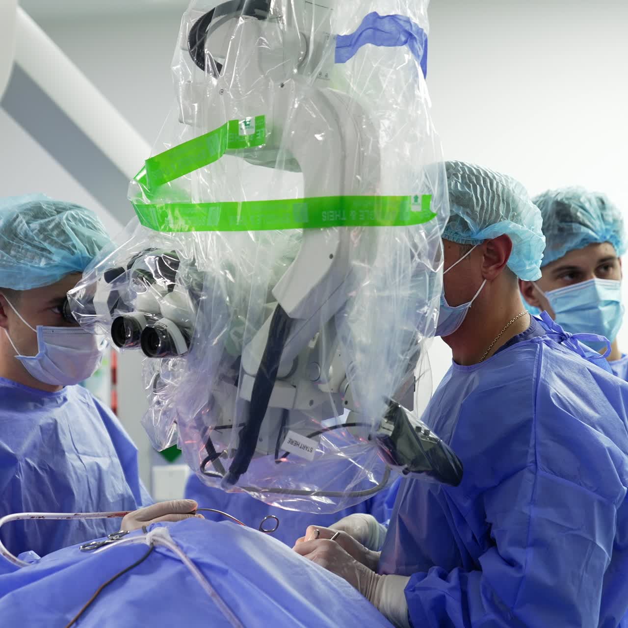 Professional surgeons look into microscope covered in plastic. Surgical operation with usage modern technologies