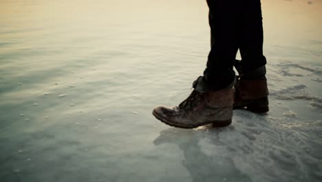 walking with dirty old leather boots over salt into the dead sea, israel