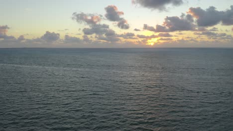 Stunning-Orange-Sunrise-Behind-Cumulus-Clouds-over-Ocean