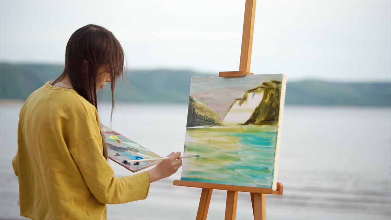 Woman painting a landscape at the beach