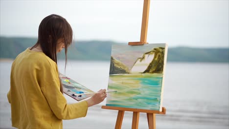 woman painting a landscape at the beach