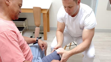 applying bandage, prosthetist assisting patient with prosthetic leg in clinic