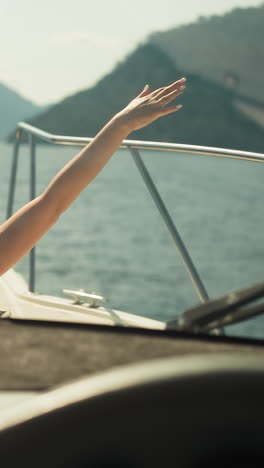 woman rejoices summer vacation by traveling on modern yacht soaking up sun and observing beauty of sea. lady looks out of cabin hatch stretching arms out to sides