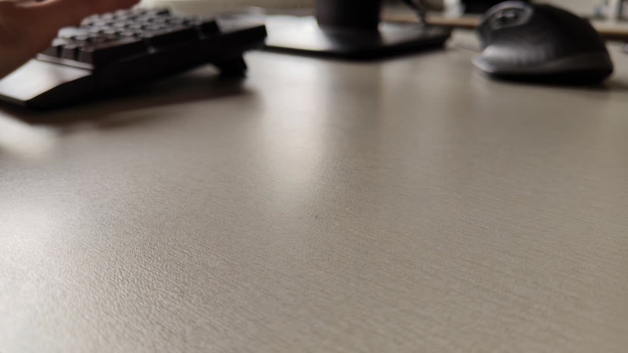Person's forearm reaching, gripping, tilting keyboard on office desk for adjusting, copy space