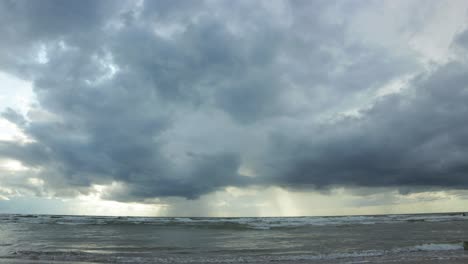 time lapse of dramatic dark storm clouds moving fast over the baltic sea at liepaja towards the camera, low angle wide shot