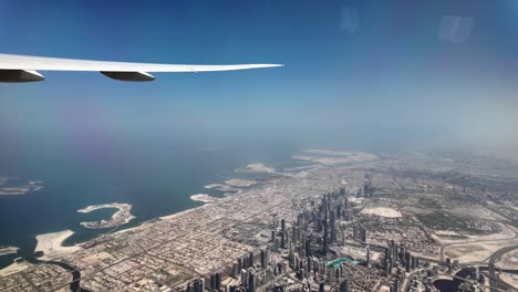 airplane is flying over dubai, offering a breathtaking view of the city's impressive skyline, characterized by towering skyscrapers and the iconic palm jumeirah