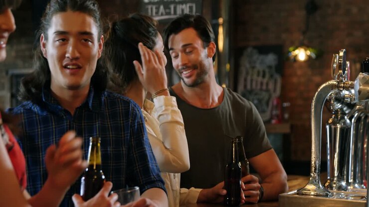 Gruppo di amici sorridenti mentre bevono una bottiglia di birra