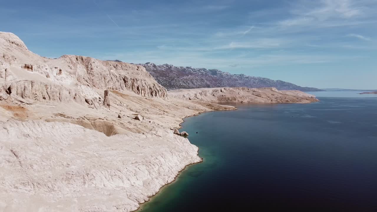 vuelo de drones sobre montañas rocosas y mar, revelando montañas en el fondo