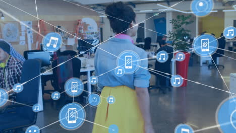 animation of network of digital icons against diverse man and woman talking to each other at office