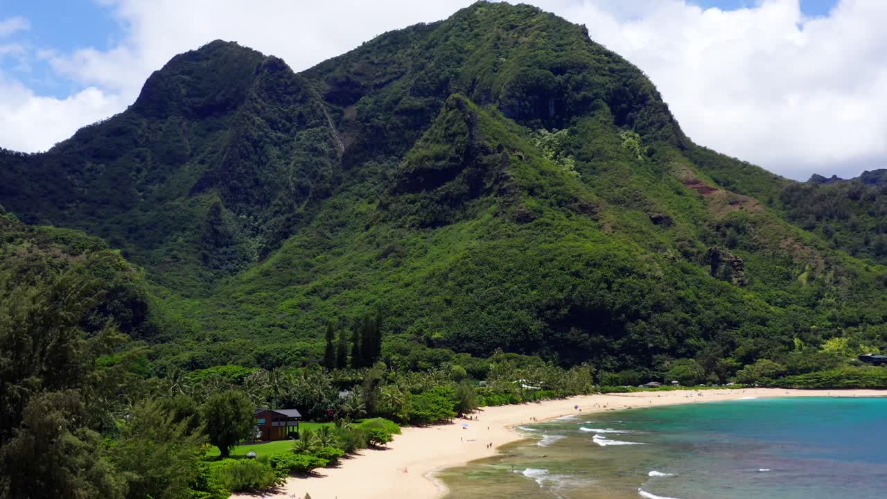 4K aerial footage of Tunnels Beach on the North Shore of Kauai, Hawaii. This drone shot captures the crystal-clear turquoise waters, coral reefs, and dramatic backdrop of lush green mountains
