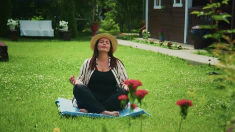 woman meditating on a blue mat in a serene garden surrounded by blooming flowers and greenery