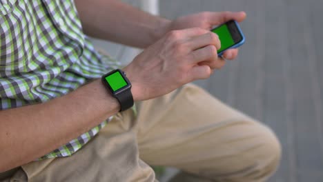 hombre usando teléfono inteligente y reloj inteligente al aire libre