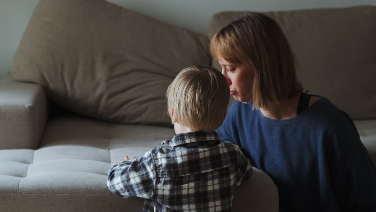 niño y madre leyendo un libro mientras se sienta al lado del sofá