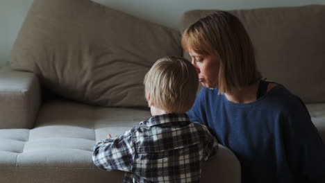 Junge-Und-Mutter-Lesen-Ein-Buch,-Während-Sie-Neben-Dem-Sofa-Sitzen