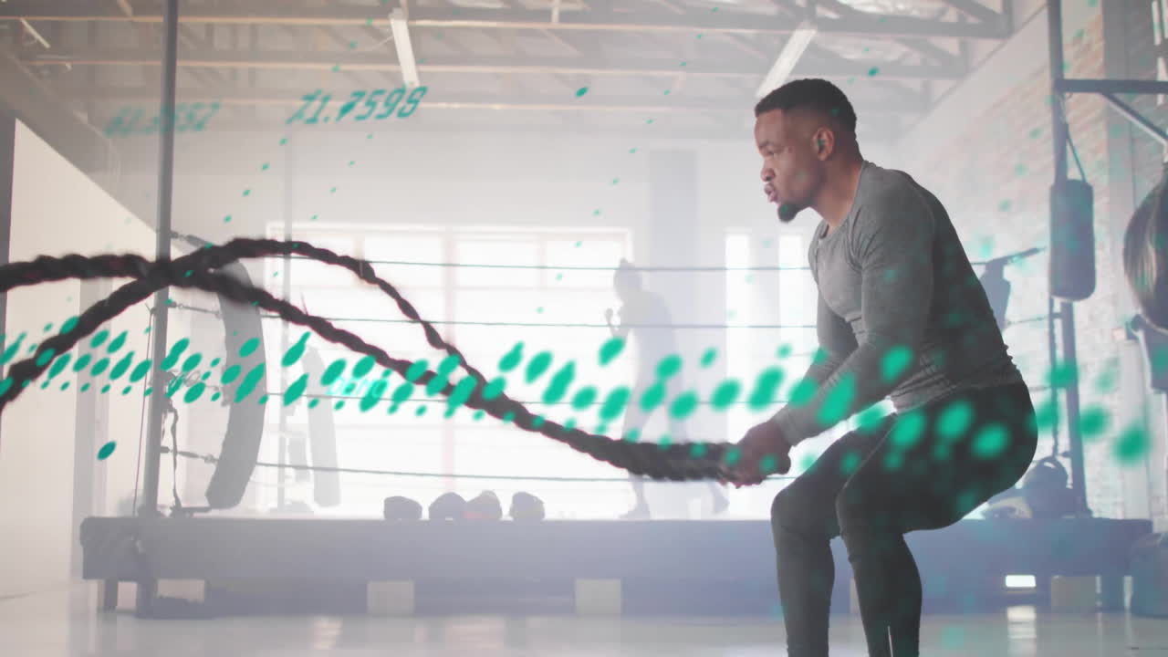 Man exercising with battle ropes, digital data animation overlaying gym scene