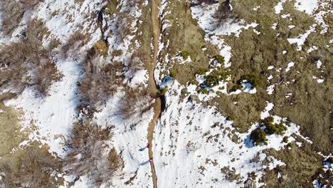 excursionistas caminando por un pequeño sendero de montaña cubierto de nieve en invierno tiro de drones