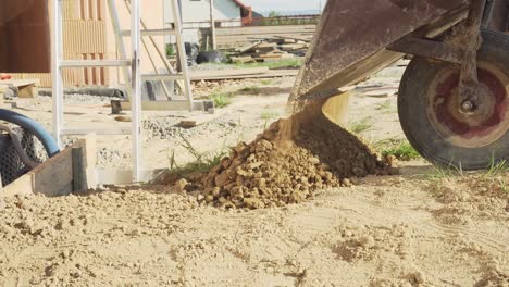 static shot of throwing out dirt from wheelbarrow on house construction site