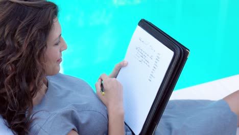 Pretty-brunette-taking-notes-on-deckchair