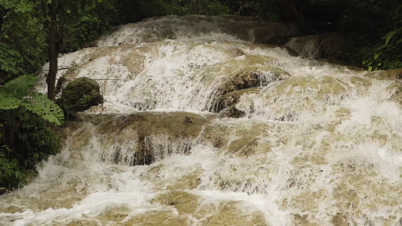 Potente cascata a gradoni che scorre sulle rocce calcaree nella riserva naturale di Pu Luong, Vietnam. Scenario di giungla tropicale con acqua dolce impetuosa, vegetazione lussureggiante e atmosfera incontaminata di ruscello di montagna