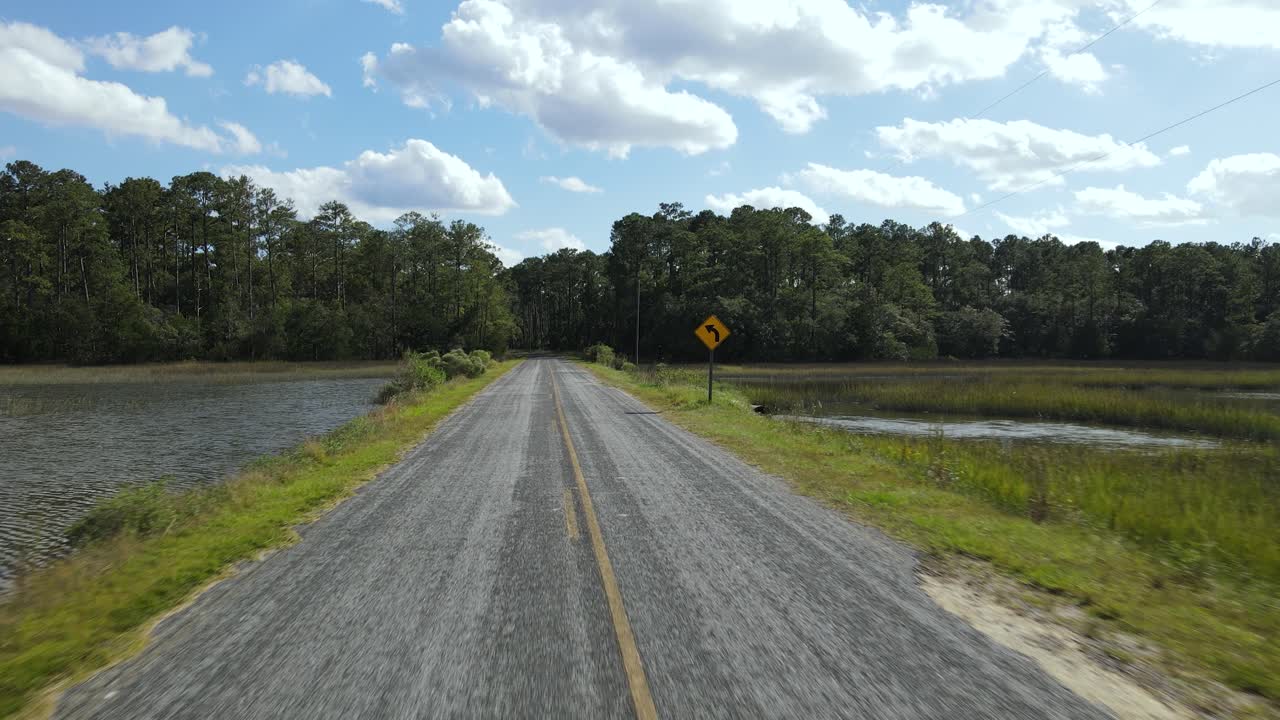 Passing a yellow left turn side on an empty asphalt road with yellow lines in the countryside of south carolina