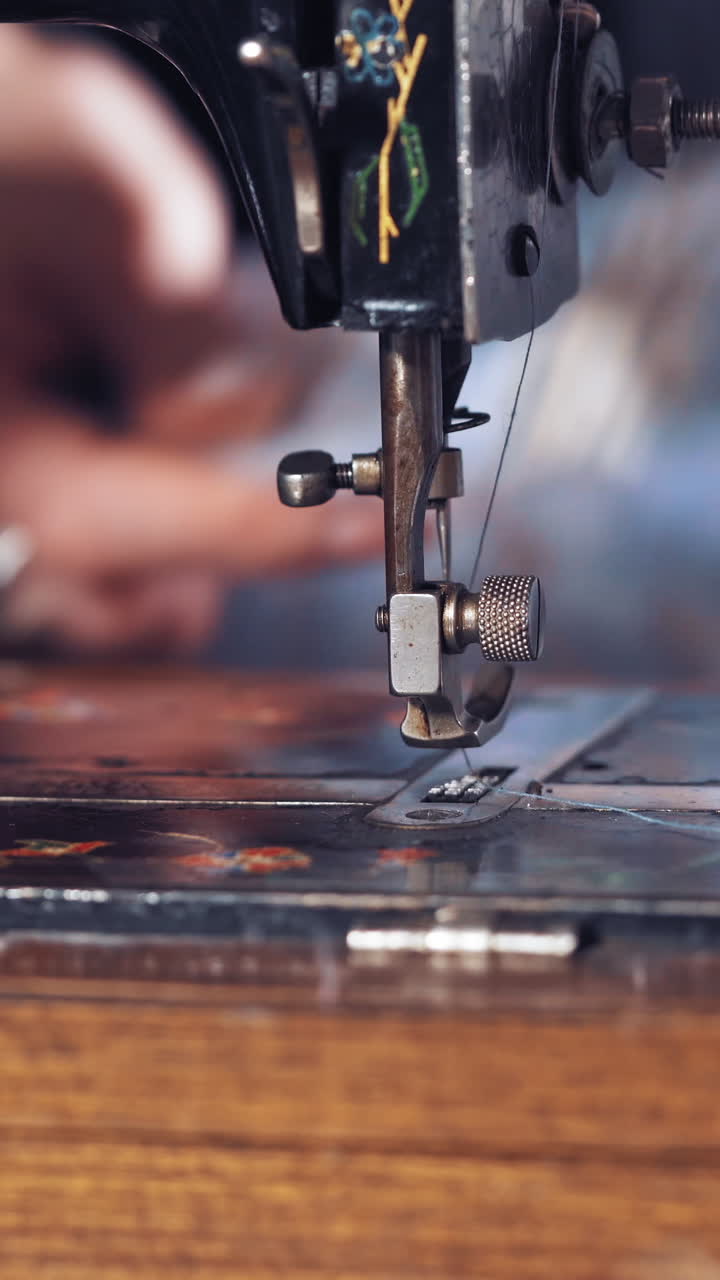 Seamstress sews clothes on machine. Close up of sewing machine and item of clothing Vertical video